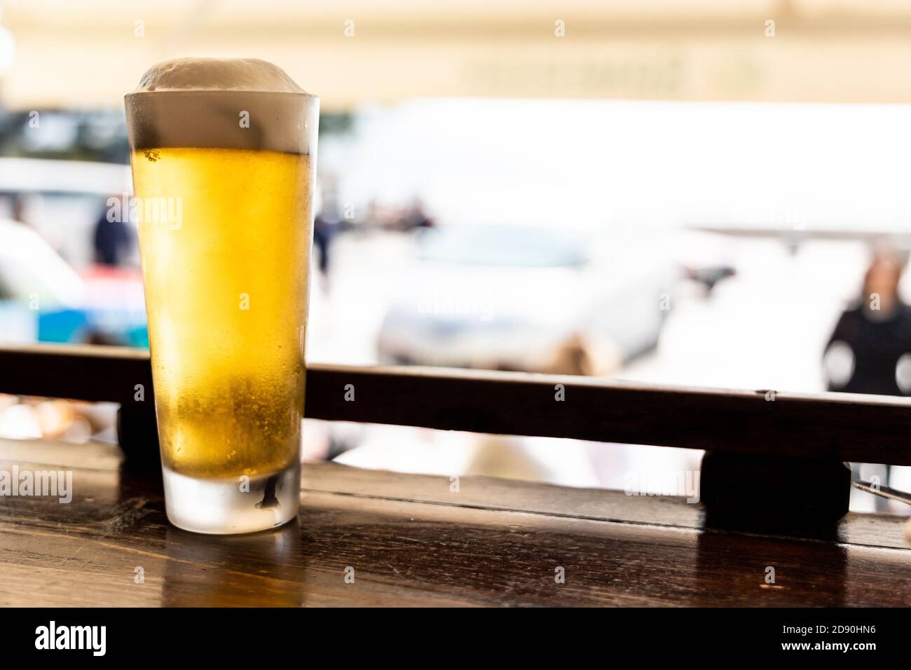 Ein Glas goldenes kaltes Bier auf der Theke gegenüber der Straße Stockfoto