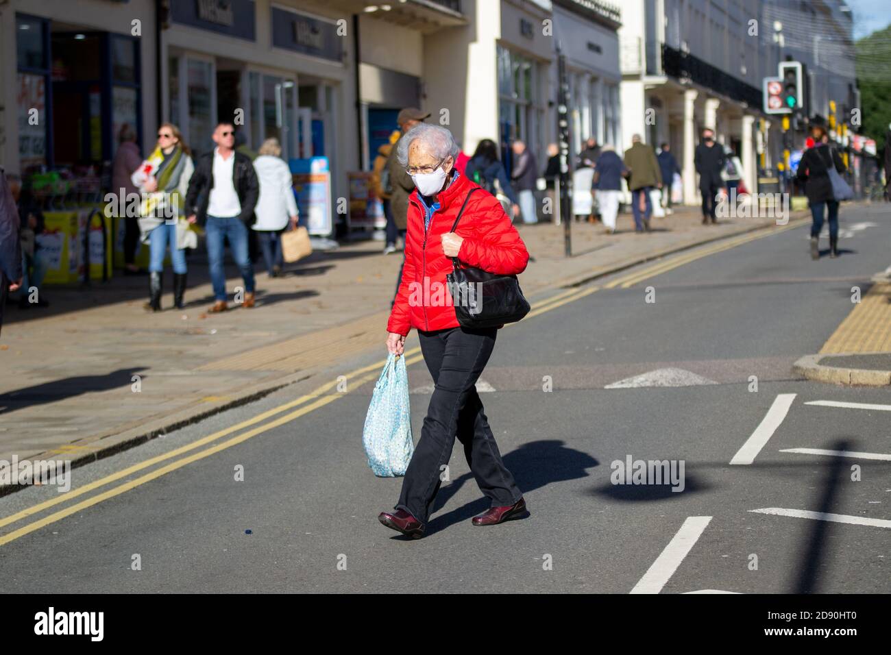 Ältere Dame in roter Jacke mit Shopping in Leamington Spa, Warwickshire, als ein weiterer Monat lang Lockdown Webs für Großbritannien Stockfoto