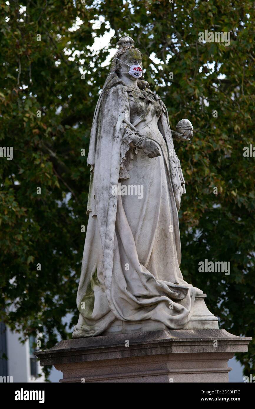 Königin Victoria Statue trägt eine Gesichtsmaske, die sagt "STOP HS2' in Leamington Spa Stockfoto