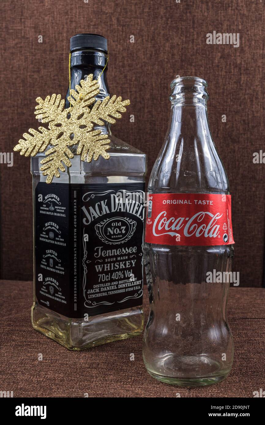 Weihnachtsfeiertagskonzept, Jack Daniel buttle weihnachtsbaum und Coca Cola, perfekte Kombination Geschenk, Gold flattern Schneeflocken Dekoration Stockfoto