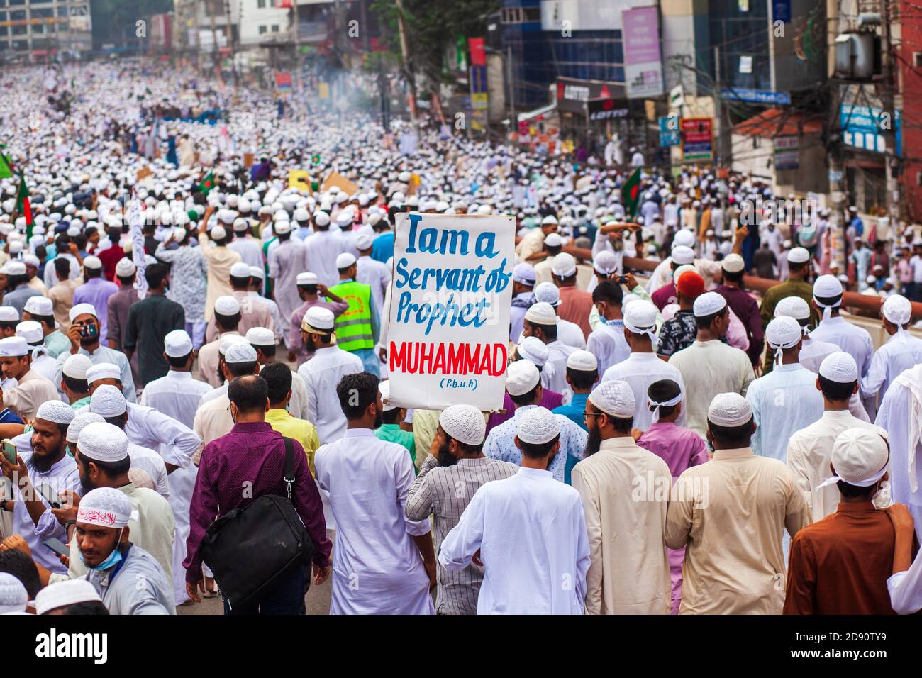 Ein Aktivist des Hefazat-e-Islam Bangladesh zeigt ein Plakat während des Anti-Frankreich-protestmarsches in Dhaka.Tausende Hefazat-e-Islam Bangladesh Führer und Aktivisten nehmen an einem Anti-Frankreich-protestmarsch Teil, der zum Boykott französischer Produkte aufruft und den französischen Präsidenten Emmanuel Macron für seine Bemerkungen anprangert ‘nicht aufzugeben Cartoons Darstellung Propheten Mohammed’. Hefazat-e-Islam Bangladesch hat der Regierung ein 24-Stunden-Ultimatum zur Schließung der französischen Botschaft in Dhaka gestellt. Stockfoto