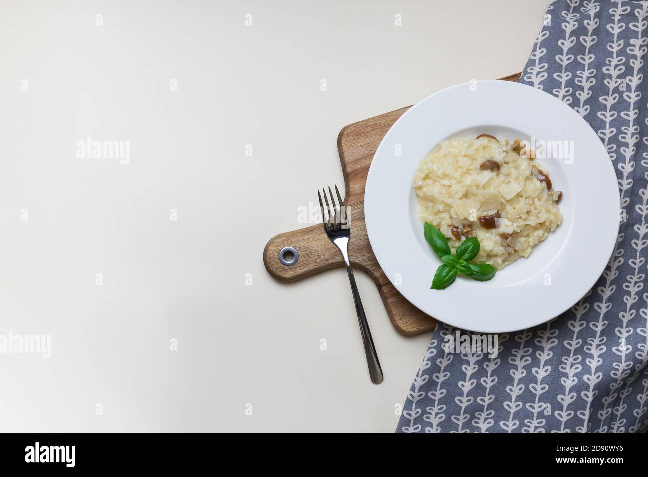 Vegetarisches Gourmet-Pilzrisotto auf weißem Teller, gelber Hintergrund, Blick von oben. Risotto ist ein norditalienisches Reisgericht, das mit Brühe gekocht wird, bis es eine cremige Konsistenz erreicht. Stockfoto
