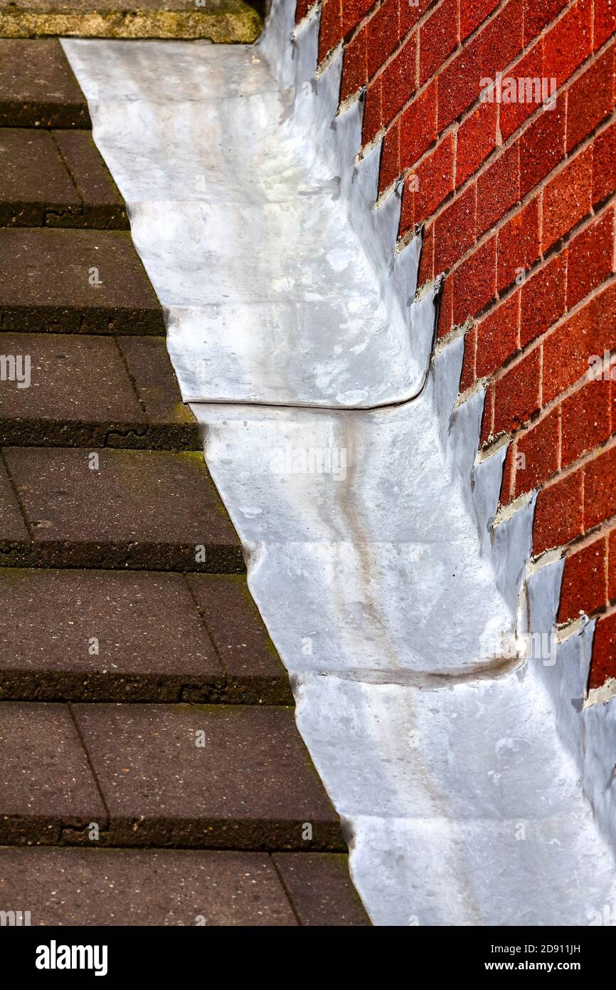 Stufenleiter blinkende Dachrinnen schaffen eine wasserdichte Abdichtung Zwischen Dachziegel und Ziegelwand auf einem Haus Stockfoto