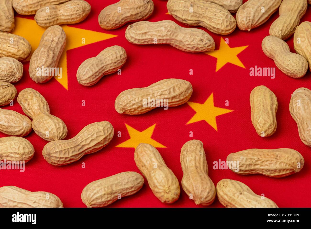 Nahaufnahme von Erdnüssen in Schale auf Flagge Chinas. Konzept der Erdnussanbau, Handel, Zölle und Marktpreis Stockfoto