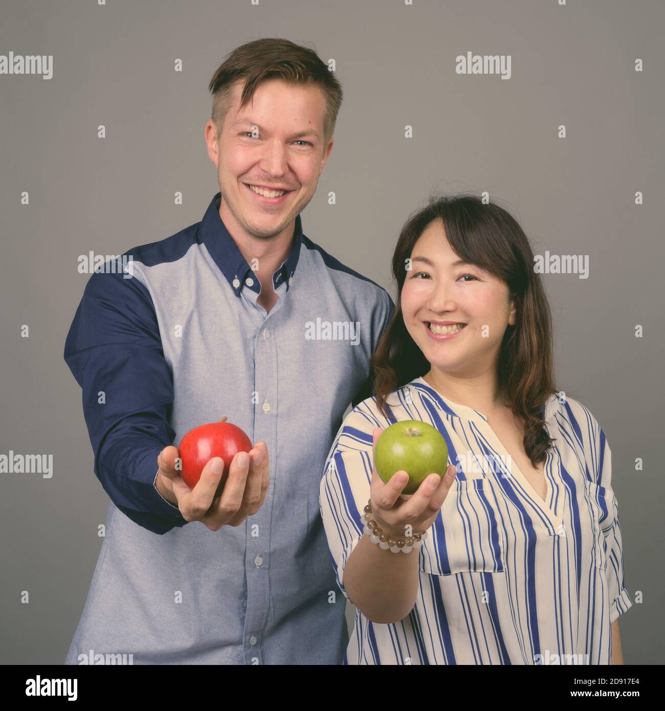 Junge gut aussehende Geschäftsmann und reifen asiatischen Geschäftsfrau vor grauem Hintergrund Stockfoto