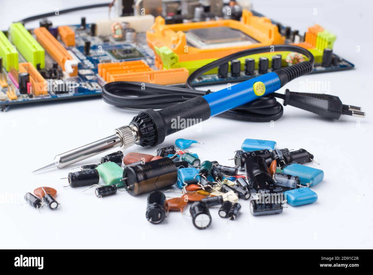 Lötkolben auf dem Hintergrund einer Computerplatine und Kondensatoren im Weichfokus. Das Konzept von Reparatur und Service Stockfoto