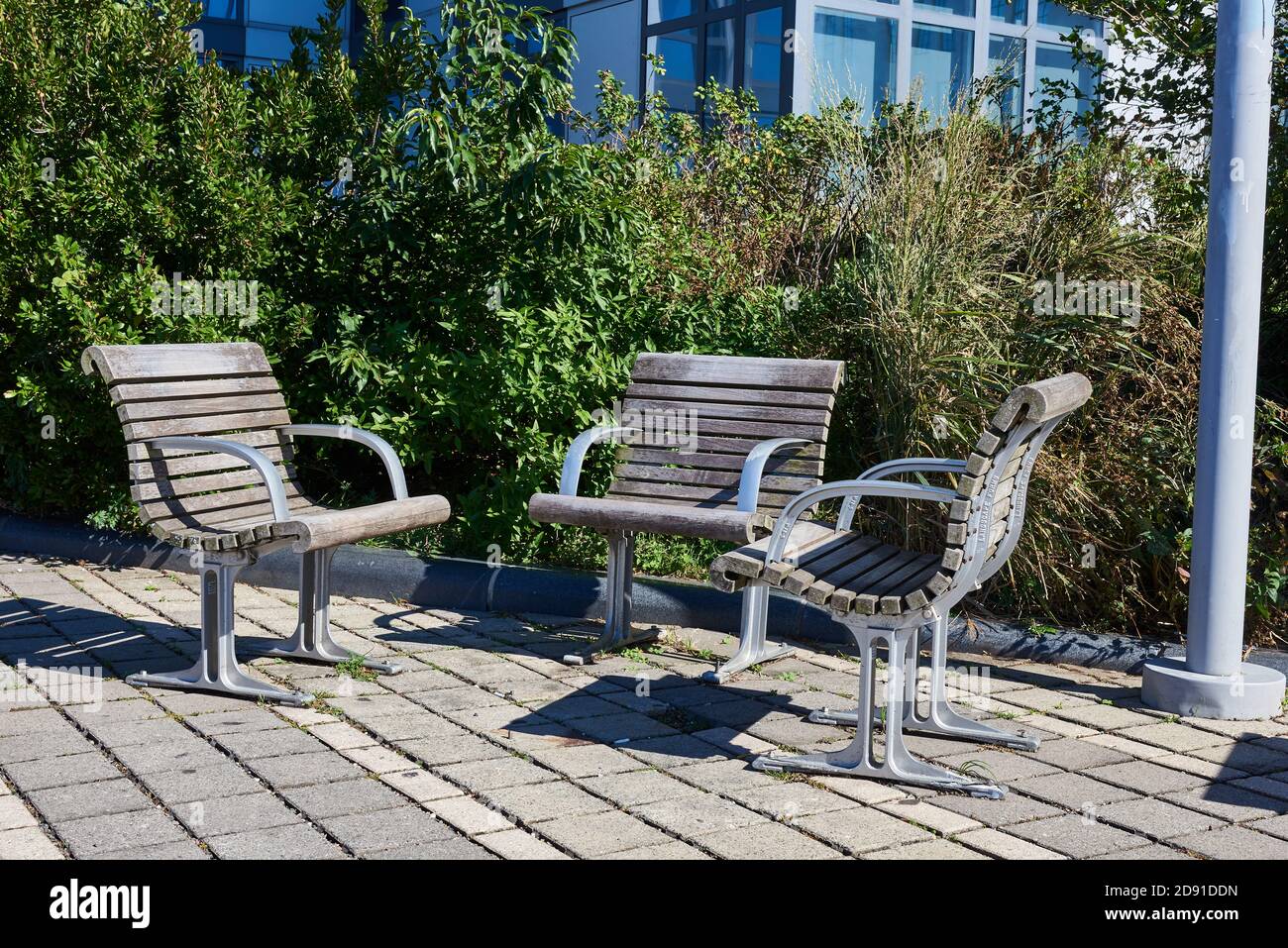 Drei Outdoor-Parksessel aus Metall und verwittertem Holz sitzen nebeneinander, um Gespräche zu ermöglichen. Stockfoto