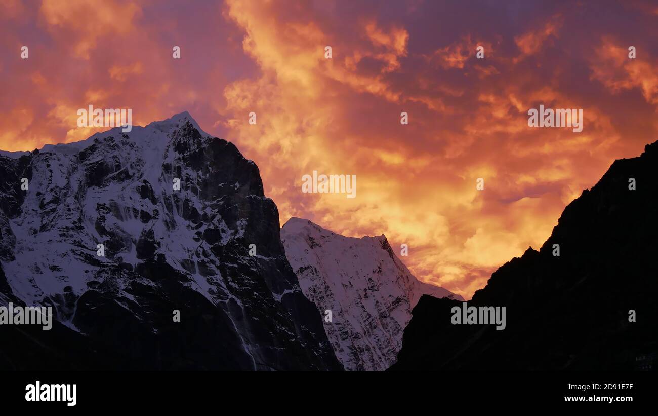 Atemberaubender Sonnenuntergang über eisbedeckten Bergen im Himalaya in der Nähe des Dorfes Thame, Khumbu, Nepal mit einem dramatischen, farbenfrohen Himmel, der wie Feuerflammen aussieht. Stockfoto