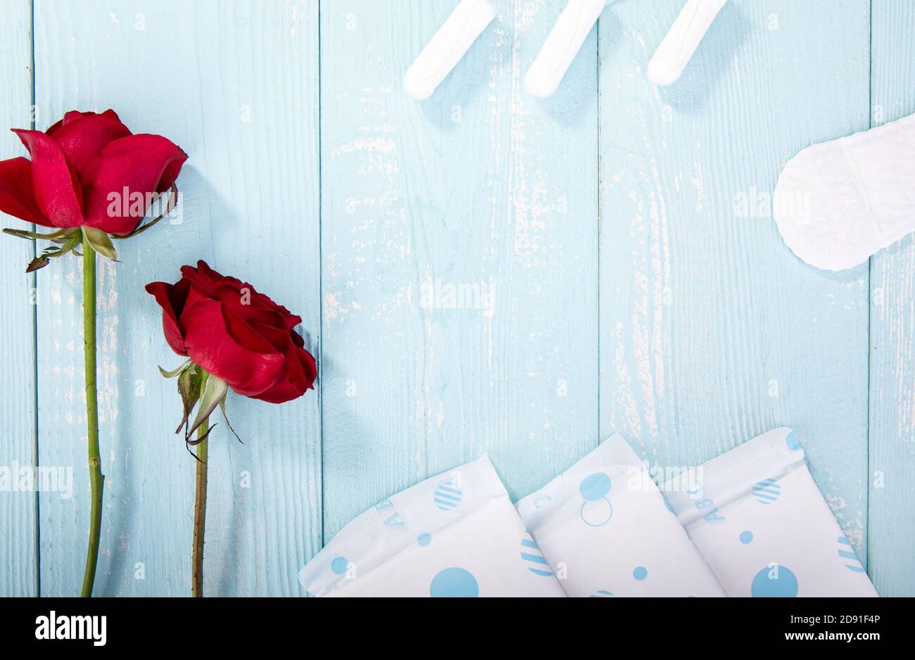 Rosen, Sanitäranlagen und Tampons auf blauem Holzhintergrund mit Platz für Text Stockfoto