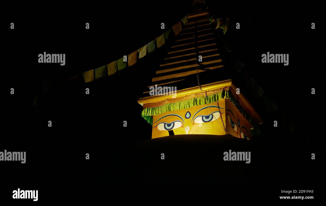 Nahaufnahme der gelben Spitze einer beleuchteten buddhistischen Stupa (religiöses Denkmal) in der Nacht mit zwei Augen und Gebetsfahnen in Namche Bazar. Stockfoto
