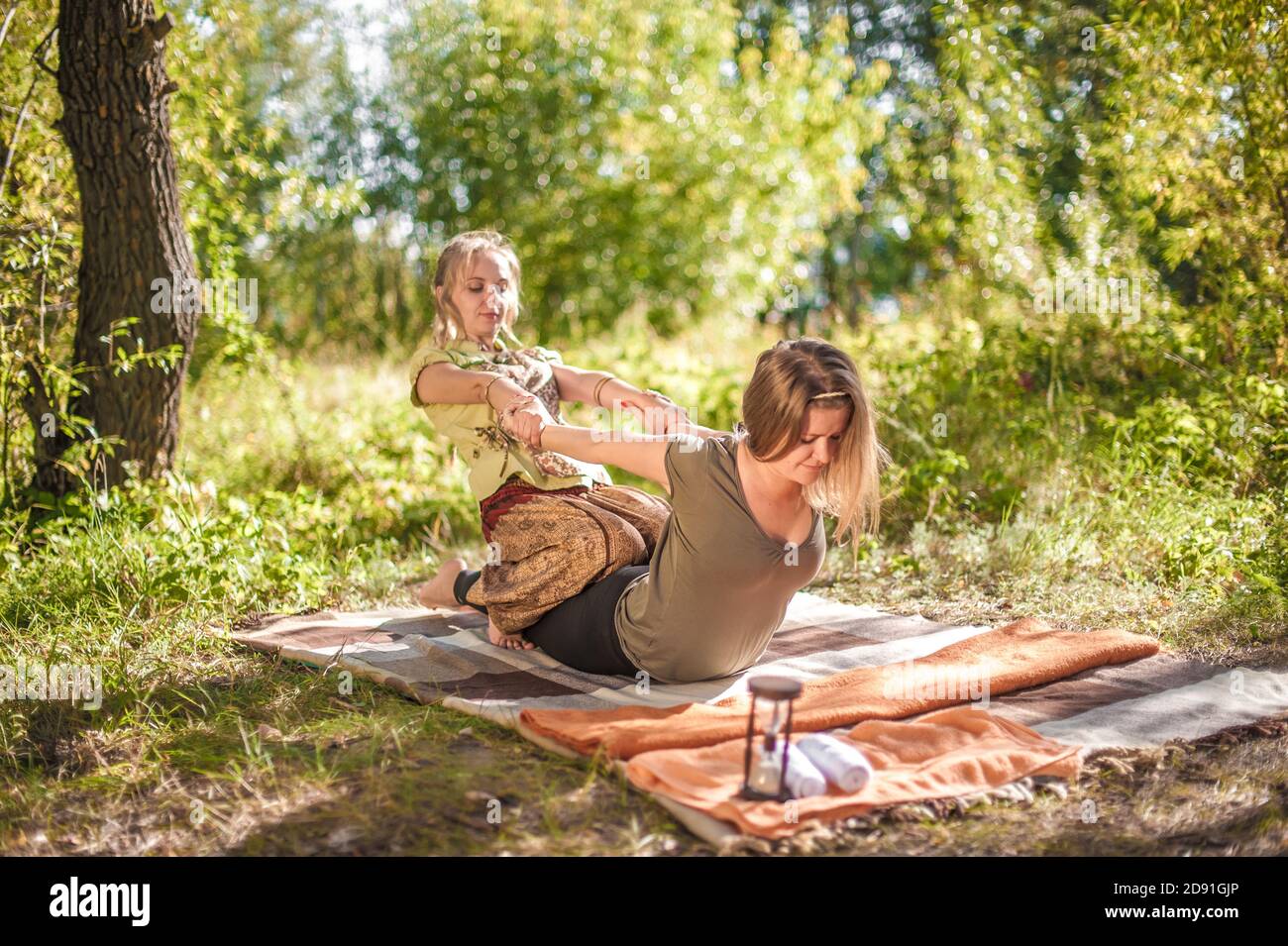 Massageexperte wendet ihre Massagefähigkeiten auf ihren Klienten auf dem Gras an. Stockfoto