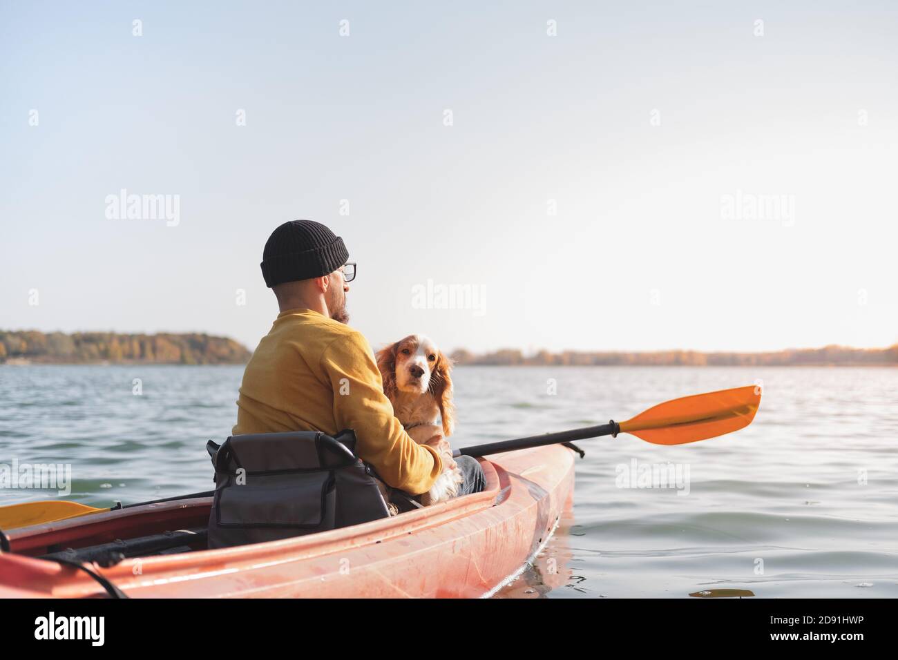 Mann mit Hund im Kanu auf dem See. Junger Rüde mit Spaniel im Kajak-Ruderboot, aktive Freizeit mit Haustieren, Begleitung, Abenteuerhunde Stockfoto