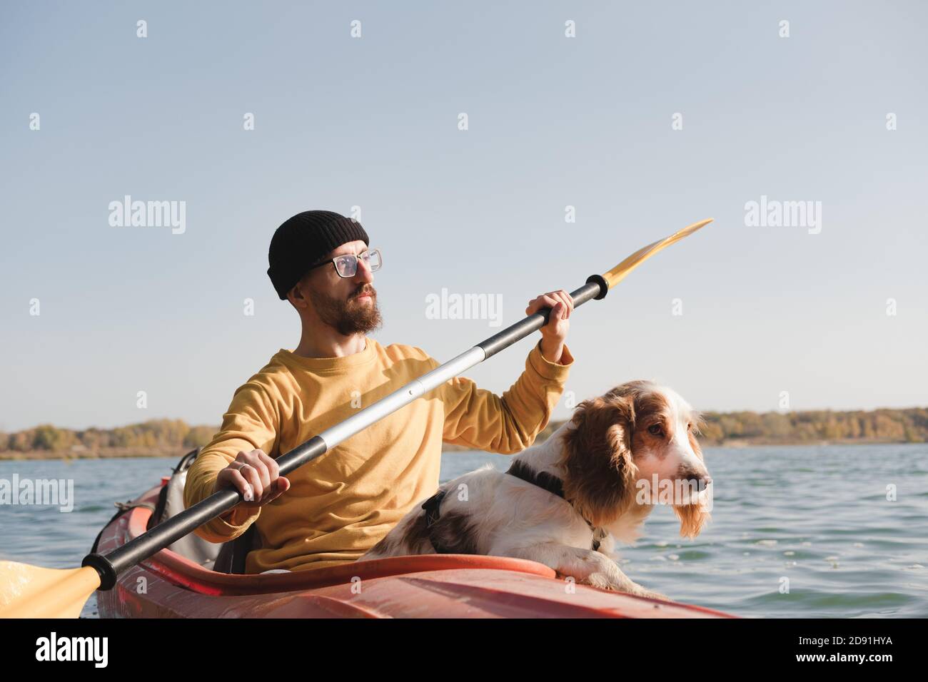 Kajakfahren mit Hunden: Mann rudert ein Boot auf dem See mit seinem Spaniel. Aktive Erholung und Abenteuer mit Haustieren, Kanu fahren mit Hund Stockfoto