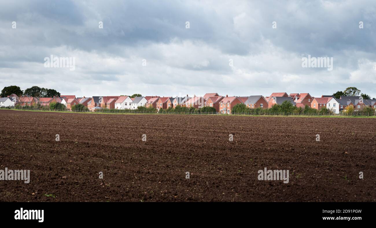 EEngland UK - 10.07.2020: Panoramablick auf neue dichte Wohnsiedlung mit einem gepflügten Feld im Vordergrund, der aufdringliche Entwicklung in to Coun darstellt Stockfoto