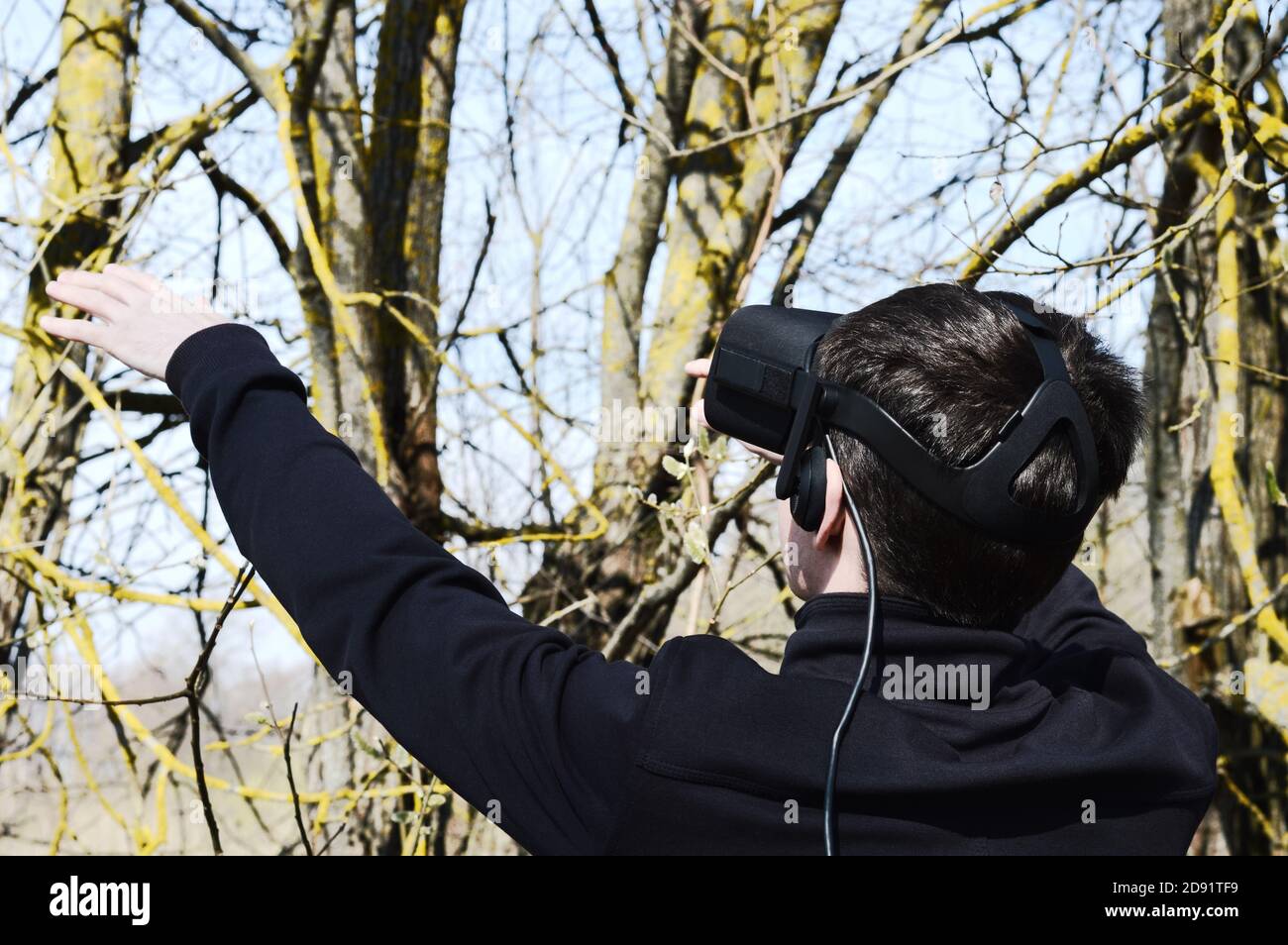 Junger Mann versuchen VR-Brille im Freien und erleben virtuelle Technologien Interagieren Sie mit der tatsächlichen Natur Stockfoto