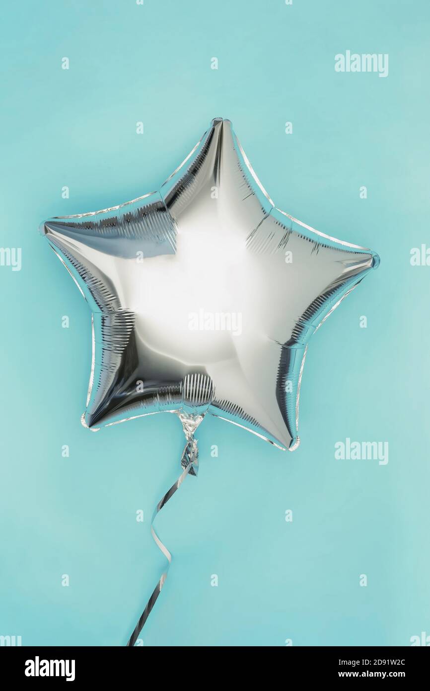 Ein silberner Glitter-Folienballon in Sternform, isoliert auf Pastell Hintergrund Stockfoto