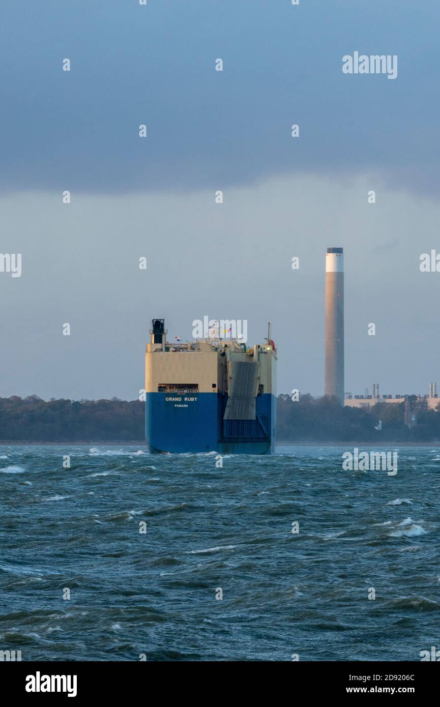 Das große Rubinkarrierschiff, das in southampton einfährt, dockt am Schornstein des raffineriekraftwerks fawley vorbei. Stockfoto