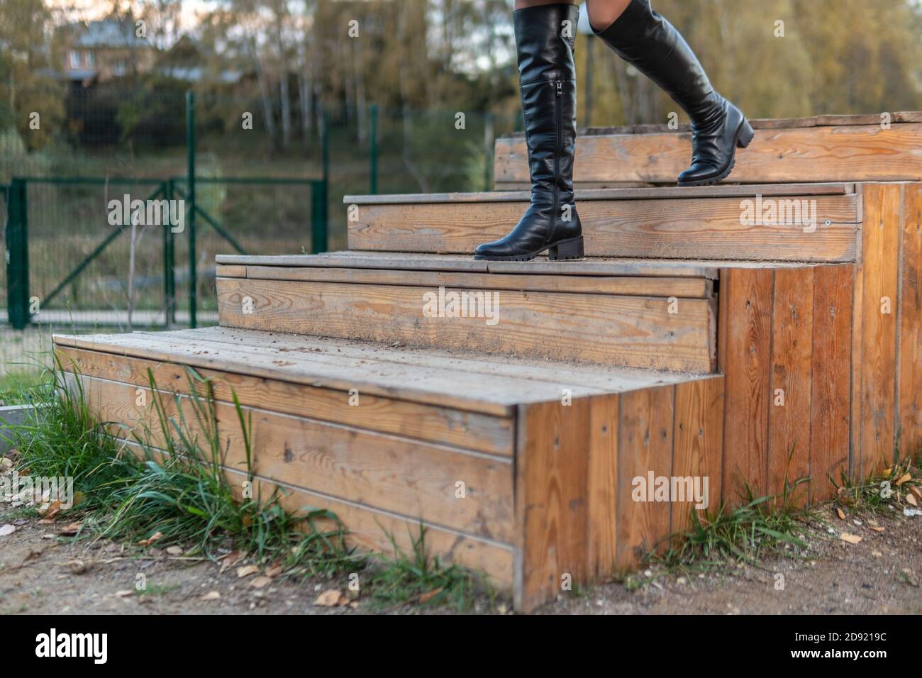 Eine fröhliche Frau geht die Treppe in Burgunder-Pall und biret, mit einem schönen Lächeln in schwarzen Kleidern, im Sturz vor dem Hintergrund eines Teiches Stockfoto