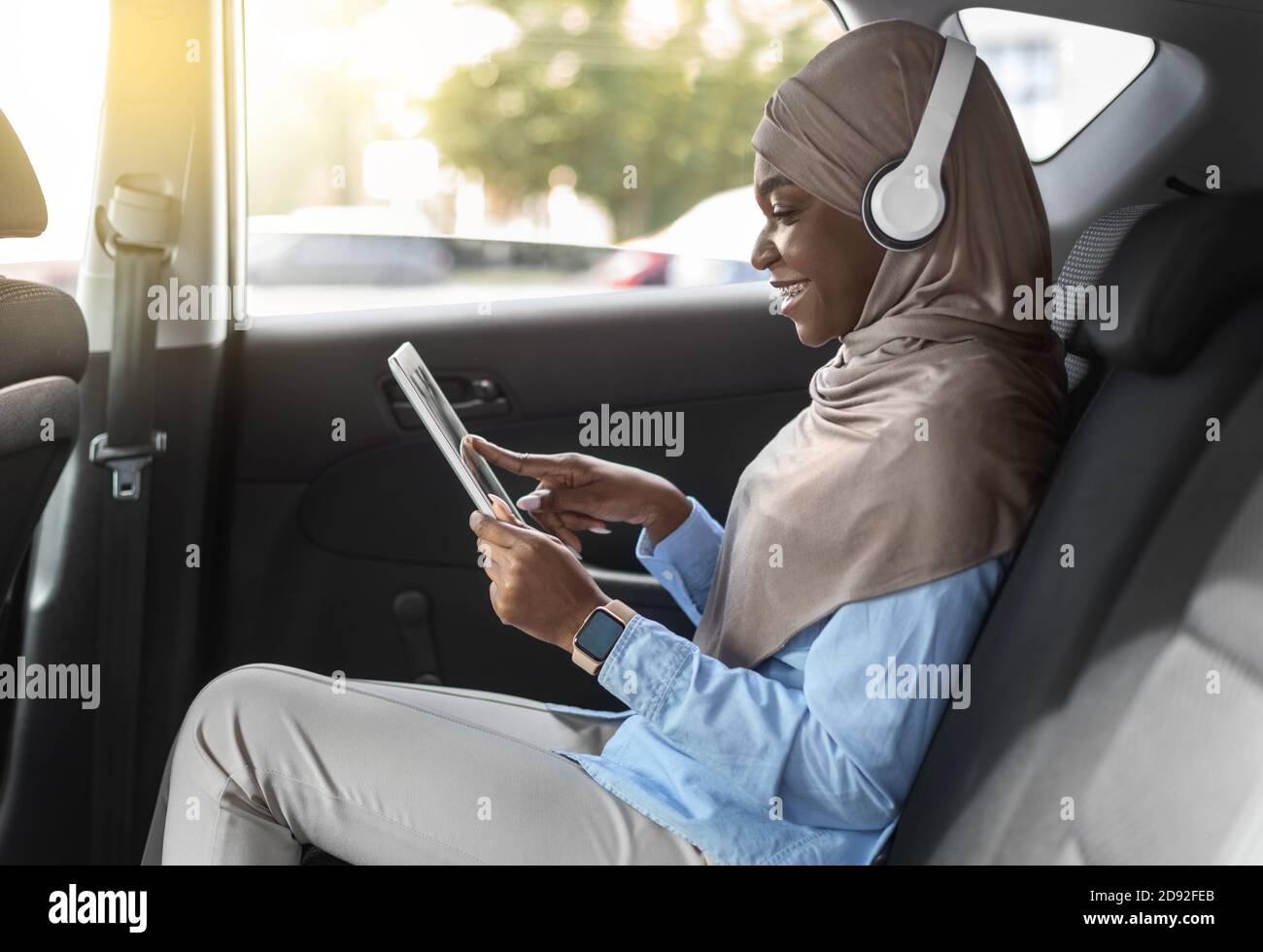 In Car Entertainment. Schwarze Muslimische Frau Mit Digitalen Tablet Während Reiten Automobil Stockfoto