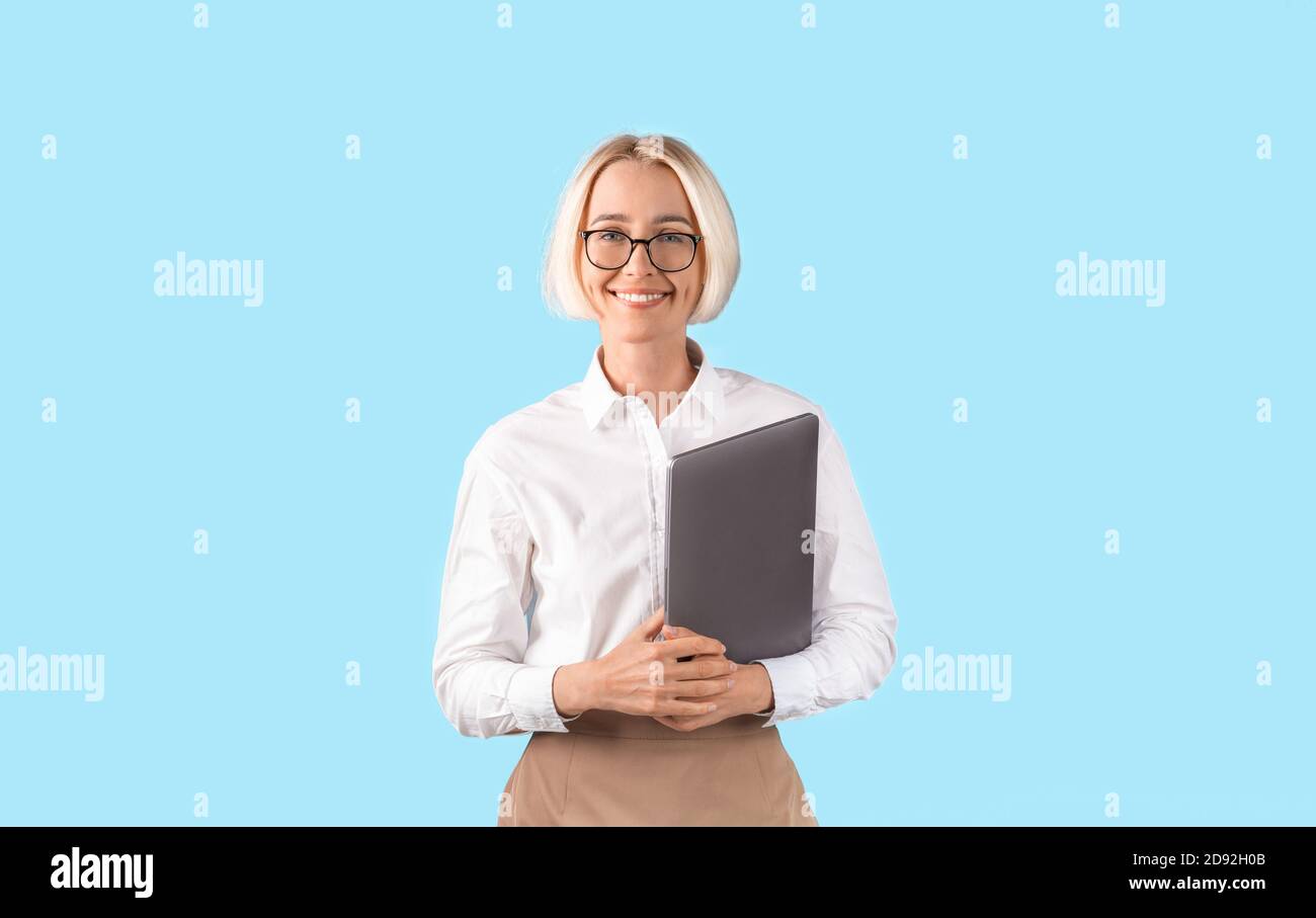 Attraktive reife Geschäftsfrau hält Tablet-Computer über blauen Studio-Hintergrund, Panorama. Online-Kommunikation Stockfoto