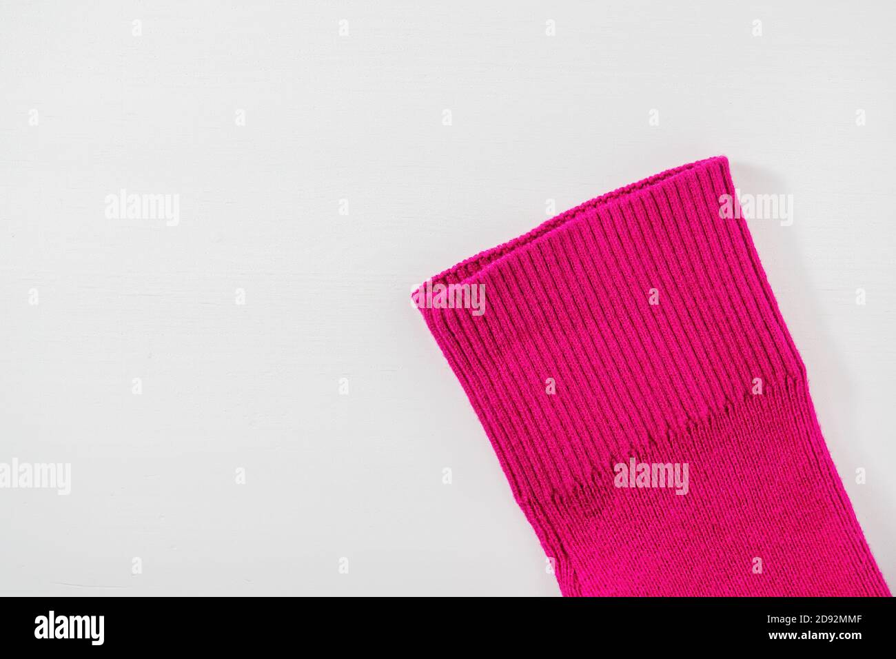 Teil des Ärmels aus rosa Strickpullover auf weißem Holzhintergrund. Draufsicht, Kopierbereich für Text. Stockfoto