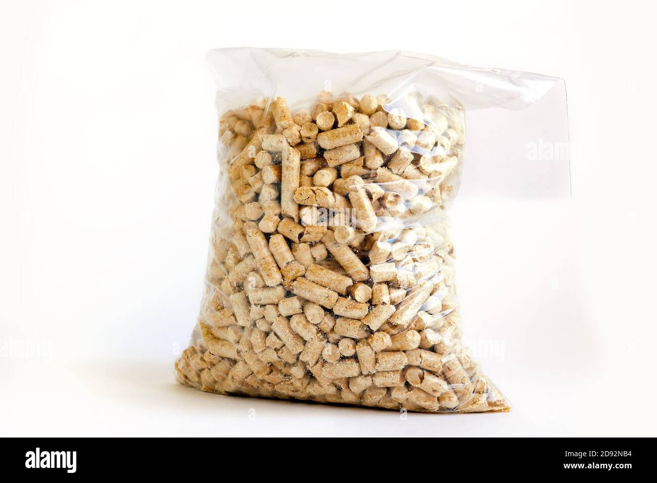 Holzpellets in Plastiktüte auf weißem Hintergrund. Katzenstreu aus frischen Kiefernkatzen in transparentem Sack Stockfoto