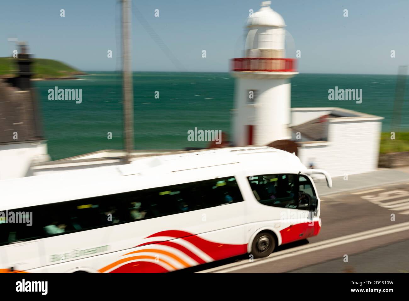 Öffentliche Verkehrsmittel Irland. Bus Eireann Bus fährt am Youghal Lighthouse an sonnigen Tagen in Youghal, County Cork, Irland. Sonniges Wetter in Irland Stockfoto