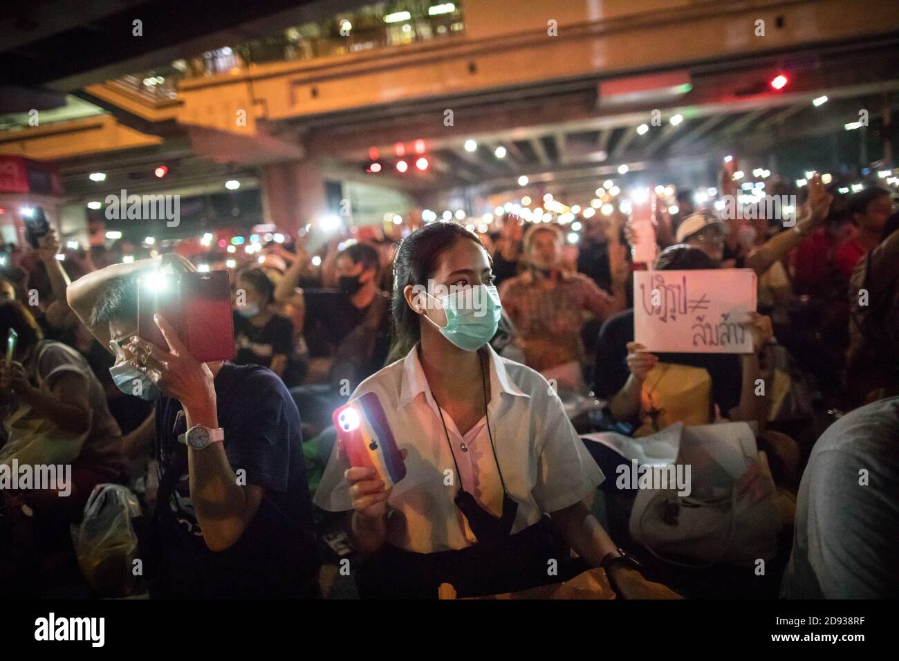 Eine Studentin und pro-demokratische Protesterin blitzen während einer regierungsfeindlichen Demonstration in der thailändischen Hauptstadt das Licht ihres Smartphones auf. Tausende von prodemokratischen Demonstranten gingen auf die Straße an der Kreuzung Tha Phra und forderten den Rücktritt des thailändischen Premierministers und die Reform der Monarchie am folgenden Tag, an dem König Maha Vajiralongkorn (Rama X) Macht erste Kommentare über prodemokratische Demonstranten, die sagen: "Wir lieben sie alle gleich" und "Thailand ist das Land des Kompromisses" außerhalb des Großen Palastes. Stockfoto