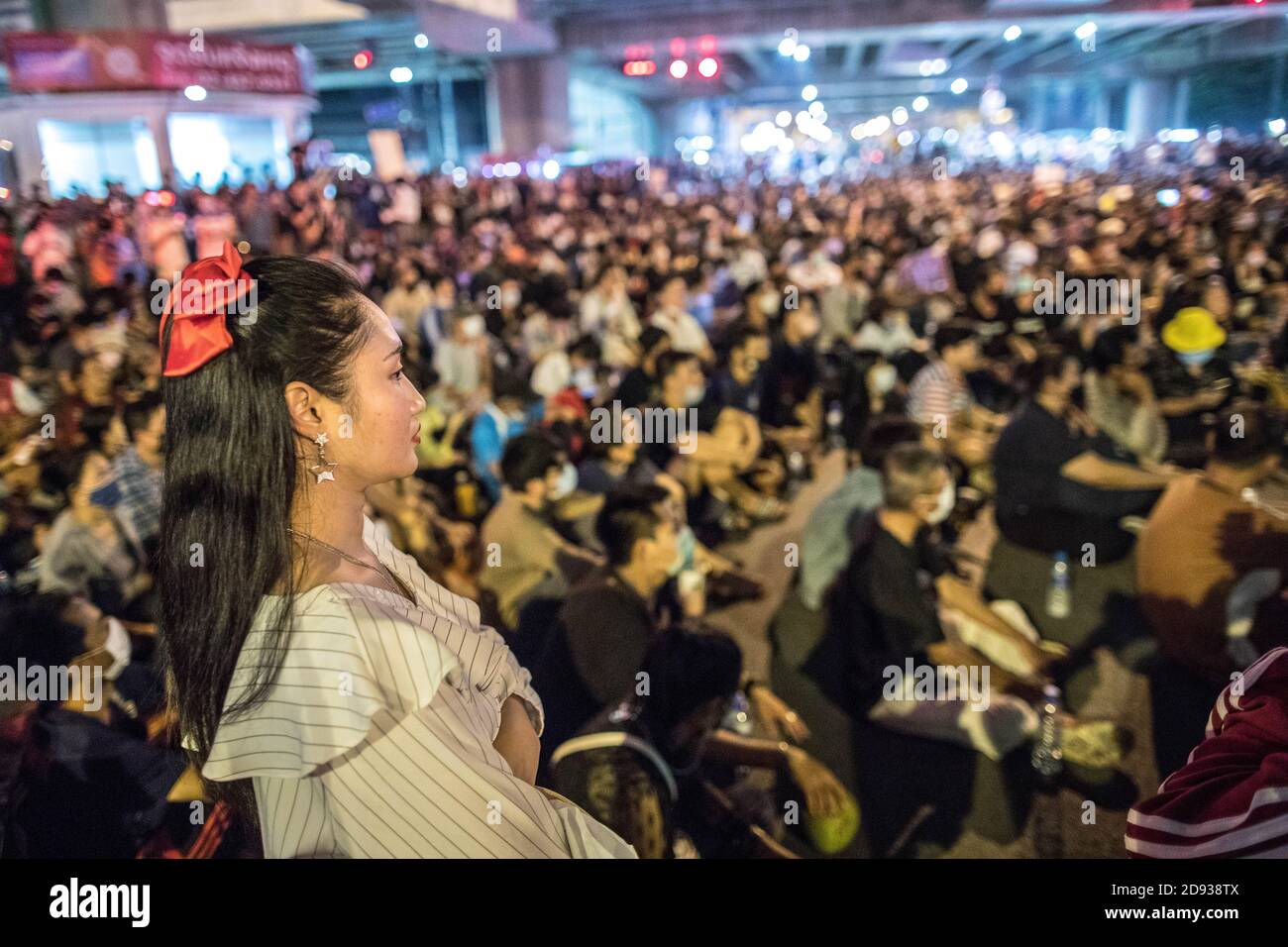 Eine prodemokratische Protesterin mit einem roten Band, das in den Haaren fest sitzt, sah die Menge während einer Anti-Regierung-Demonstration in der thailändischen Hauptstadt an. Tausende von prodemokratischen Demonstranten gingen auf die Straße an der Kreuzung Tha Phra und forderten den Rücktritt des thailändischen Premierministers und die Reform der Monarchie am folgenden Tag, an dem König Maha Vajiralongkorn (Rama X) Macht erste Kommentare über prodemokratische Demonstranten, die sagen: "Wir lieben sie alle gleich" und "Thailand ist das Land des Kompromisses" außerhalb des Großen Palastes. Stockfoto