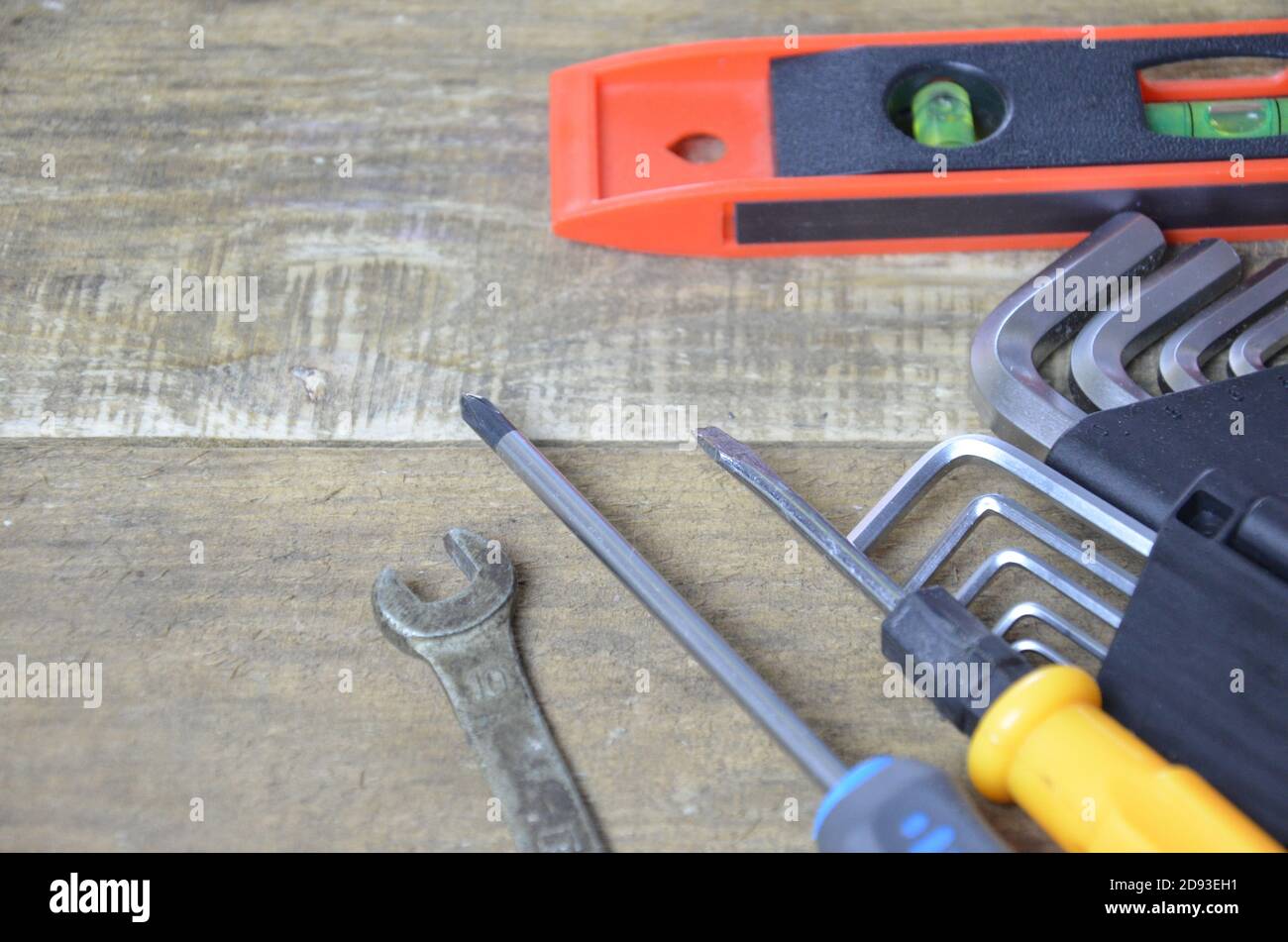 Draufsicht auf Arbeitswerkzeuge, Schraubenschlüssel, Steckschlüssel, Hammer, Schraubendreher, Zange, elektrische Bohrmaschine, Maßband, Maschinist Quadrat auf Holzbrett. Flaches Lay-Design. Stockfoto