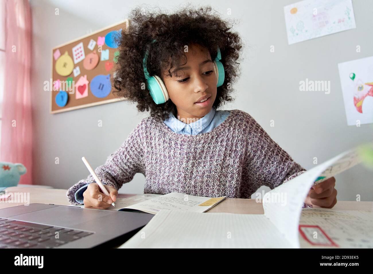 Smart african Kind Mädchen trägt Kopfhörer Lernen online Hausaufgaben zu Hause. Stockfoto