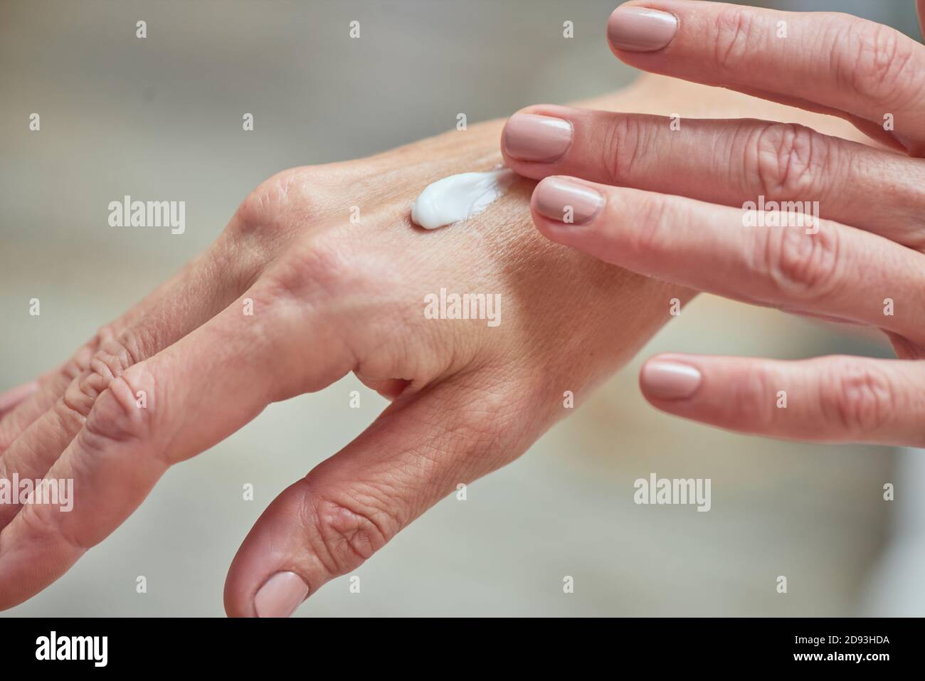 Nahaufnahme der gepflegten Frauen mittleren Alters Hände Anwendung weiße Creme. Beauty, Hautpflege und Kosmetologie Konzept Stockfoto