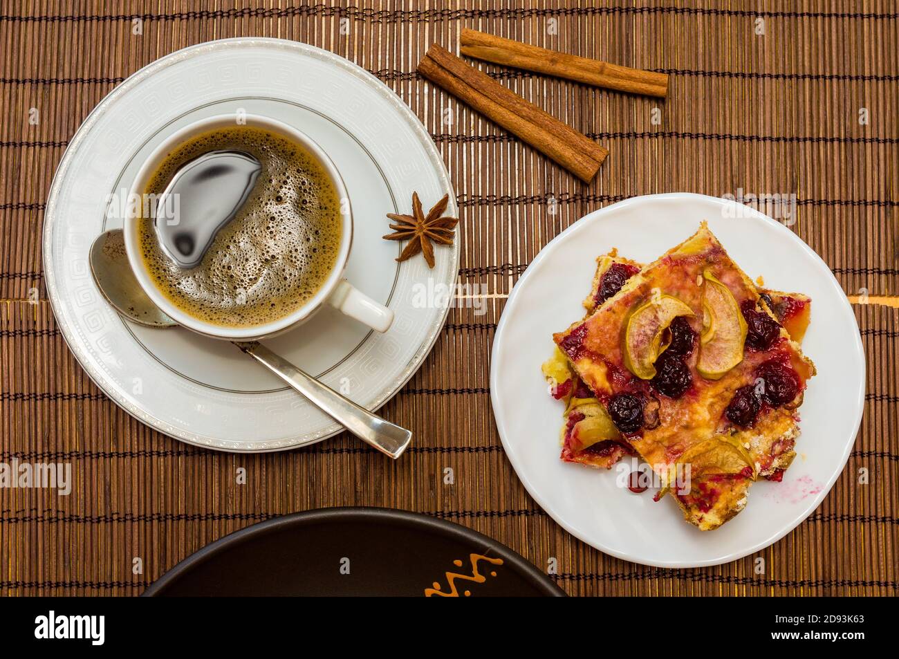 Stillleben - eine heiße Tasse schwarzen Kaffee, hausgemachte Kekse mit Obst, gebackene Äpfel auf einer Bambusmatte Stockfoto