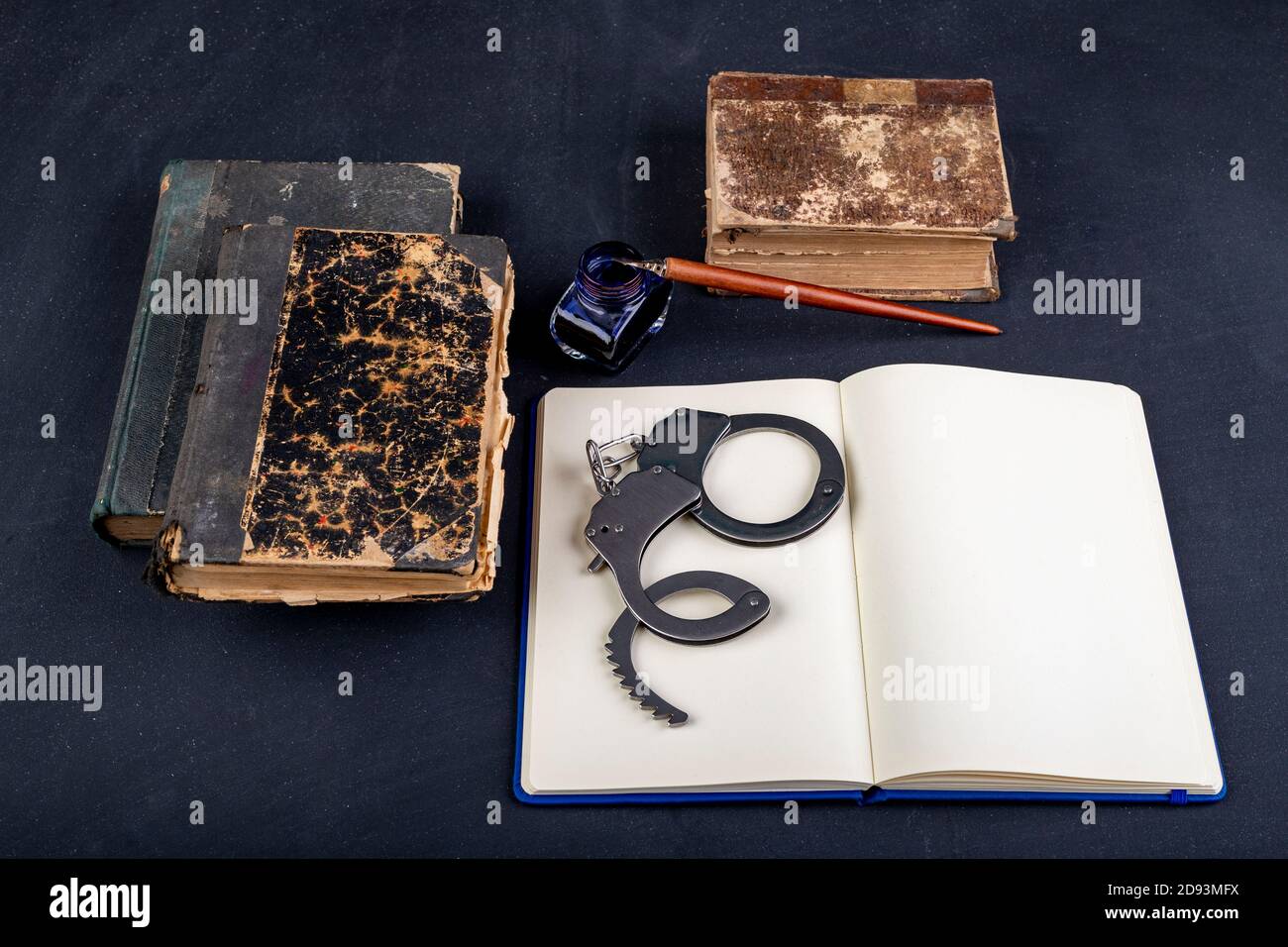 Handschellen und ein Notizbuch auf dem Tisch. Zubehör auf dem Schreibtisch der Polizeistation. Dunkler Hintergrund. Stockfoto
