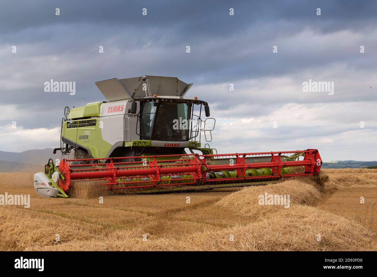 Mit dem Sky Darkening beendet ein Claas Combine Harvester die Ernte eines Gerstenfeldes in der Landschaft von Aberdeenshire im Nordosten Schottlands Stockfoto