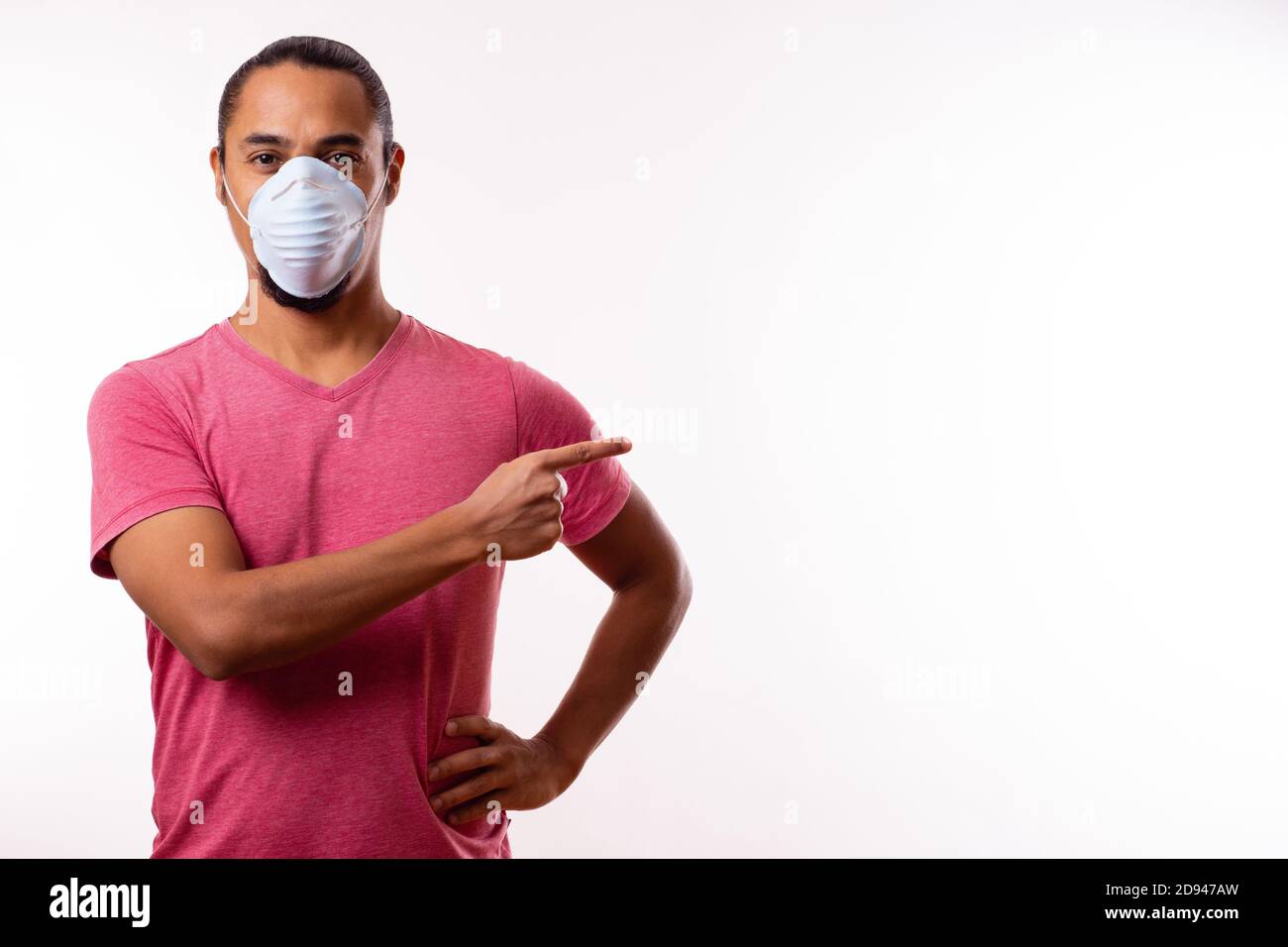 Junger glücklicher lateinischer Mann mit medizinischer Maske auf weißem Hintergrund. Speicherplatz kopieren. Coronavirus-Konzept. Stockfoto