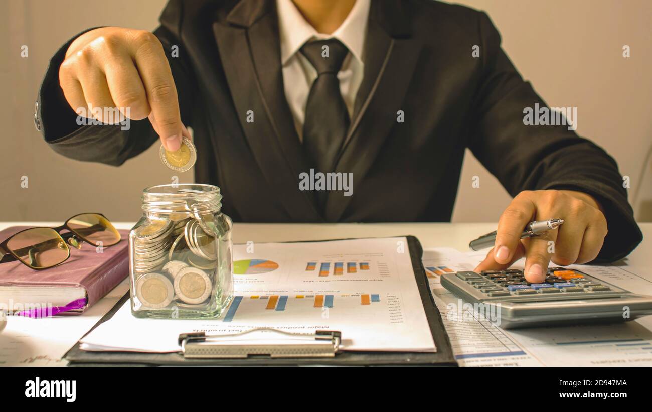 Geschäftsleute halten Geld in einer Flasche, um Geld für Anlageideen, Geldeinsparungen und nachhaltiges Investieren zu sparen. Stockfoto