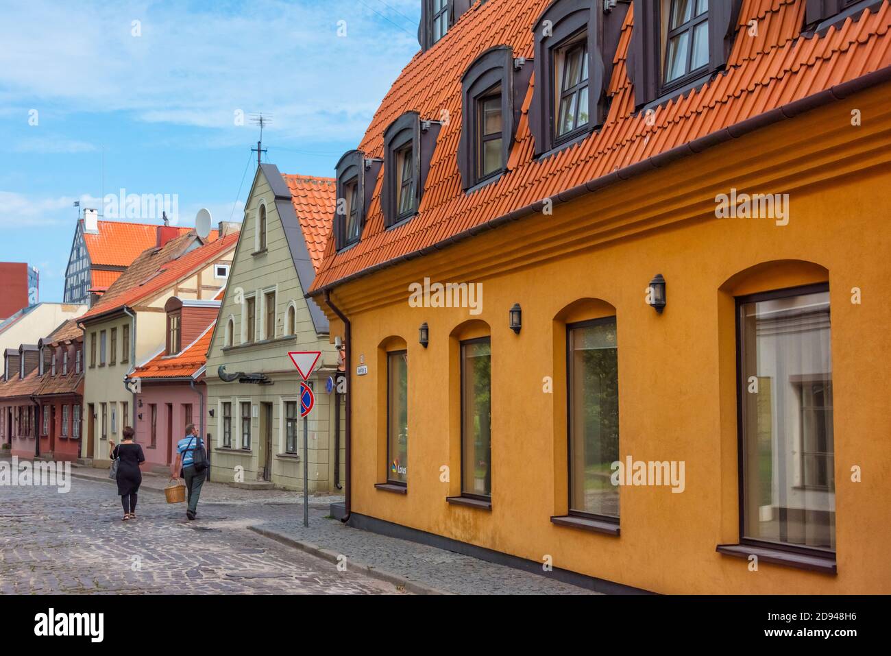 Menschen, die in der Altstadt Klaipeda, Litauen, auf einer gepflasterten Straße mit Häusern im deutschen Stil spazieren Stockfoto