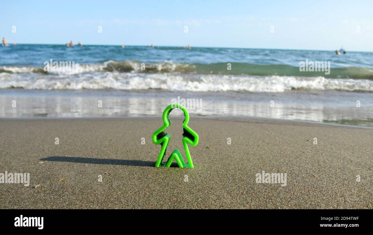 Kleine grüne Plastik menschliche Figur in den Sand vergraben Stockfoto