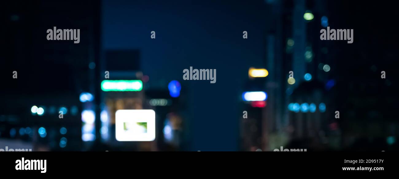 Verschwommener Bannerhintergrund der Stadt bei Nacht mit Bokeh Licht von Gebäuden und Werbeschilder Stockfoto