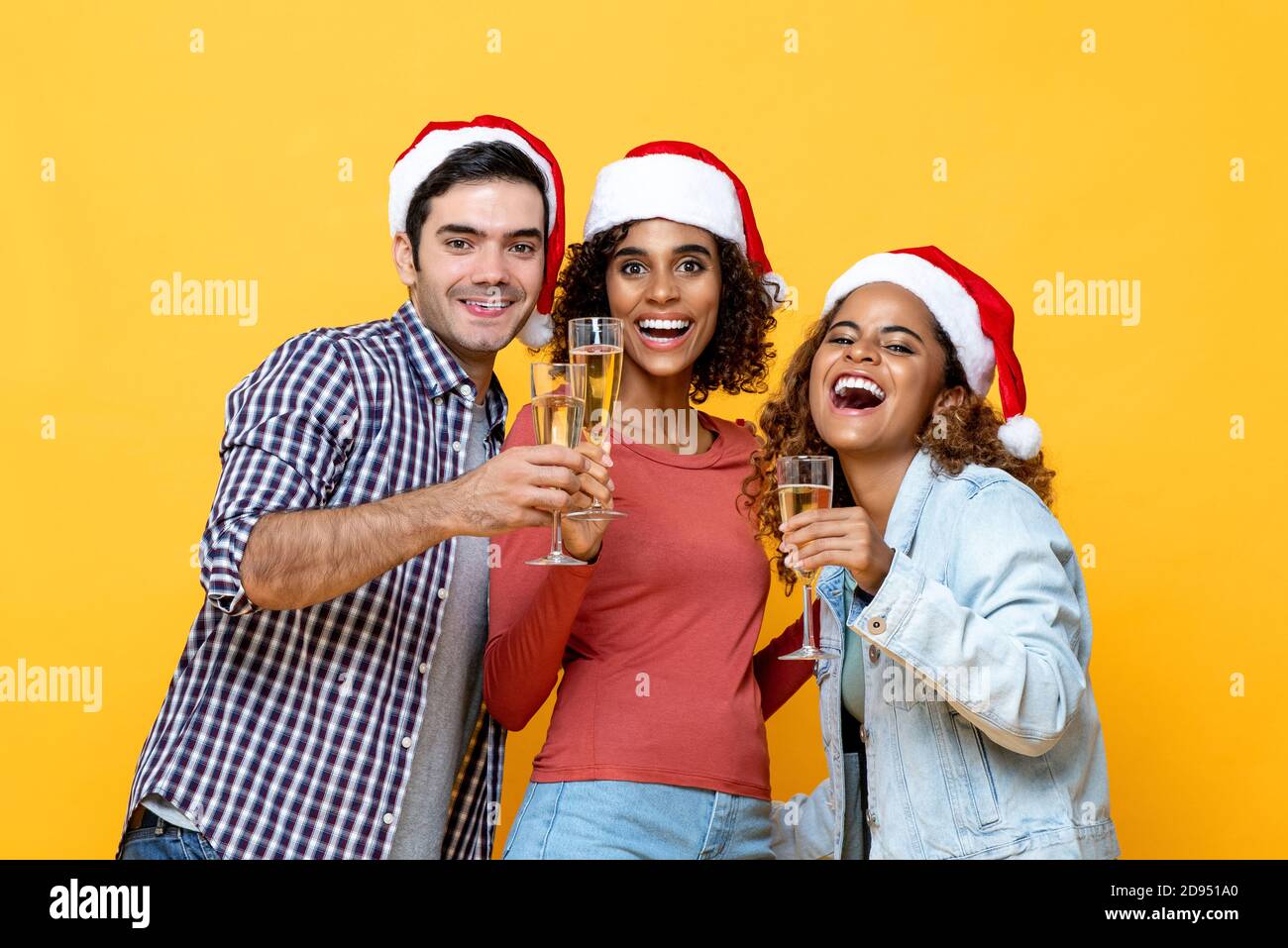 Eine Gruppe verschiedener Freunde trinkt Champagner und feiert Weihnachten auf Gelb Color Studio isoliert Hintergrund Stockfoto
