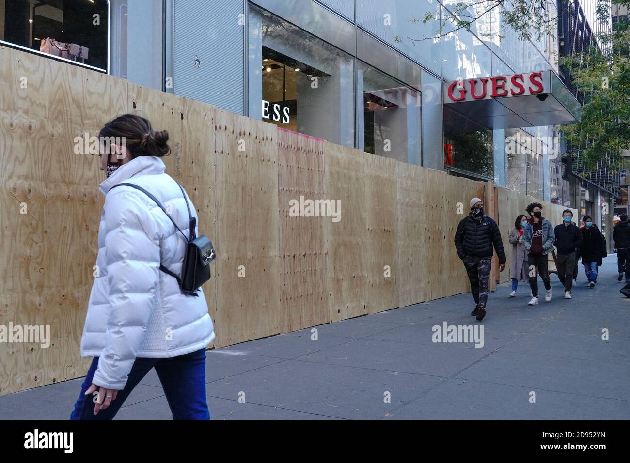 New York, USA. Oktober 2020. Menschen mit Gesichtsmasken gehen an einem vernagelten Guess Store vorbei.Immobilienbesitzer bereiten sich darauf vor, wie lokale und staatliche Beamte am Wahltag vor Gewalt im ganzen Land warnen. Kredit: John Nacion/SOPA Images/ZUMA Wire/Alamy Live Nachrichten Stockfoto