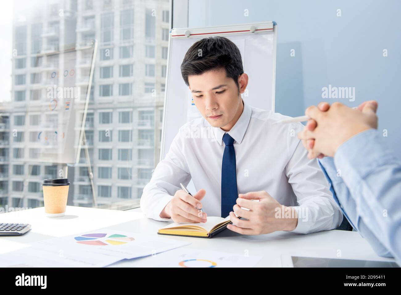 Junge neue asiatische männliche Mitarbeiter, die bei der Sitzung zur Kenntnis genommen werden Im City Office Stockfoto