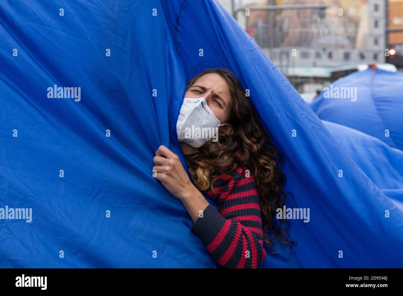 Während der Demonstration ist ein Aktivist mit Gesichtsmaske im blauen Tuch zu sehen.während der dritten internationalen Rebellion blockierte die Bewegung Extinction Rebellion die Gran Vía Straße in Madrid, um gegen die Folgen des steigenden Meeresspiegels zu protestieren. Die Bewegung, die ein 150 Quadratmeter blaues Tuch vom Callao-Platz zum spanischen Platz trägt, marschiert über die Gran Vía-Straße, um die wachsende Zahl der Menschen sichtbar zu machen, die vom Anstieg des Meeresspiegels, verursacht durch den Klimawandel, betroffen sind. Dieser Akt unter dem Namen "Wir sinken" hat die große Zahl der Todesfälle durch den Anstieg des Meeresspiegels dargestellt. Stockfoto