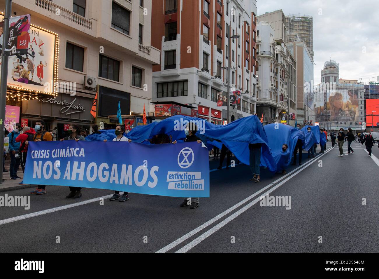 Aktivisten mit Gesichtsmasken halten ein Banner mit der Aufschrift "Klimakrise, wir sinken während der Demonstration.während der dritten internationalen Rebellion blockierte die Bewegung "Extinction Rebellion" die Gran Vía Straße in Madrid, um gegen die Folgen des steigenden Meeresspiegels zu protestieren. Die Bewegung, die ein 150 Quadratmeter blaues Tuch vom Callao-Platz zum spanischen Platz trägt, marschiert über die Gran Vía-Straße, um die wachsende Zahl der Menschen sichtbar zu machen, die vom Anstieg des Meeresspiegels, verursacht durch den Klimawandel, betroffen sind. Dieser Akt unter dem Namen "Wir sinken" hat die große Zahl der Todesfälle durch den Anstieg des Meeresspiegels dargestellt. Stockfoto