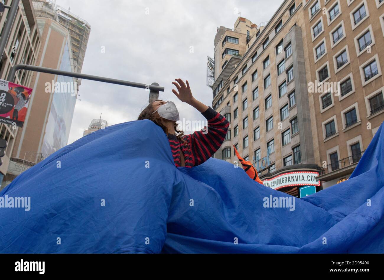 Während der Demonstration ist ein Aktivist mit Gesichtsmaske im blauen Tuch zu sehen.während der dritten internationalen Rebellion blockierte die Bewegung Extinction Rebellion die Gran Vía Straße in Madrid, um gegen die Folgen des steigenden Meeresspiegels zu protestieren. Die Bewegung, die ein 150 Quadratmeter blaues Tuch vom Callao-Platz zum spanischen Platz trägt, marschiert über die Gran Vía-Straße, um die wachsende Zahl der Menschen sichtbar zu machen, die vom Anstieg des Meeresspiegels, verursacht durch den Klimawandel, betroffen sind. Dieser Akt unter dem Namen "Wir sinken" hat die große Zahl der Todesfälle durch den Anstieg des Meeresspiegels dargestellt. Stockfoto