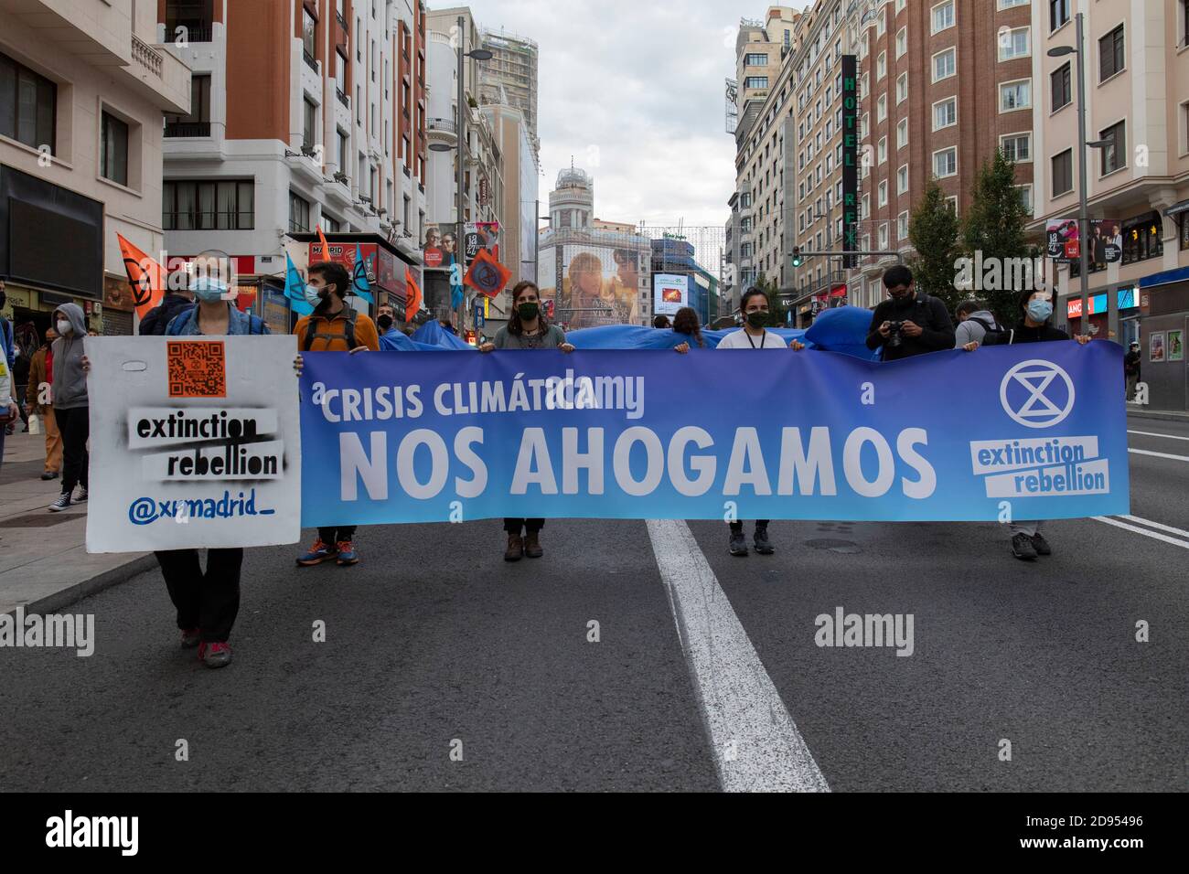 Aktivisten mit Gesichtsmasken halten ein Banner mit der Aufschrift "Klimakrise, wir sinken während der Demonstration.während der dritten internationalen Rebellion blockierte die Bewegung "Extinction Rebellion" die Gran Vía Straße in Madrid, um gegen die Folgen des steigenden Meeresspiegels zu protestieren. Die Bewegung, die ein 150 Quadratmeter blaues Tuch vom Callao-Platz zum spanischen Platz trägt, marschiert über die Gran Vía-Straße, um die wachsende Zahl der Menschen sichtbar zu machen, die vom Anstieg des Meeresspiegels, verursacht durch den Klimawandel, betroffen sind. Dieser Akt unter dem Namen "Wir sinken" hat die große Zahl der Todesfälle durch den Anstieg des Meeresspiegels dargestellt. Stockfoto