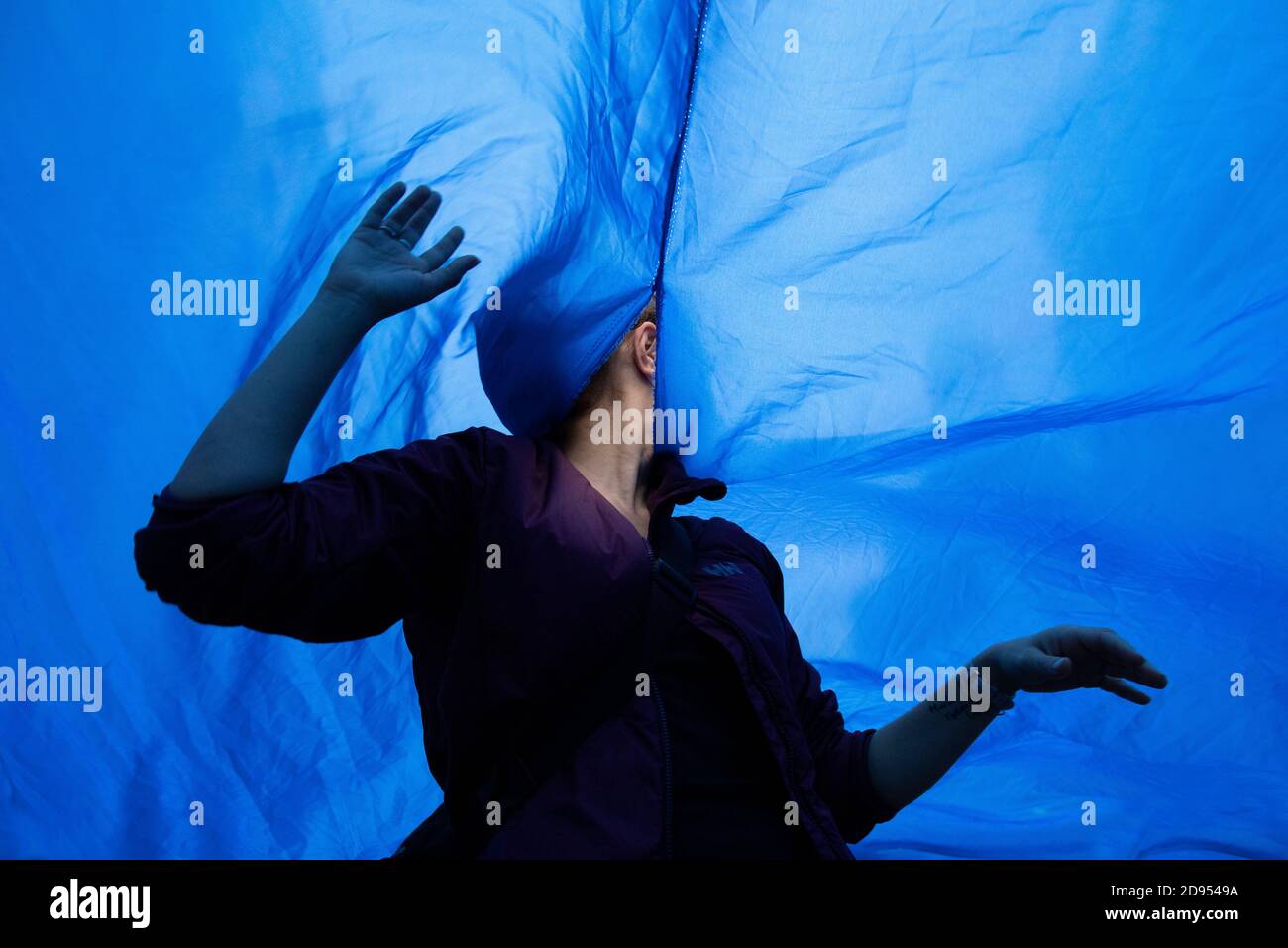 Während der Demonstration ist ein Aktivist mit Gesichtsmaske im blauen Tuch zu sehen.während der dritten internationalen Rebellion blockierte die Bewegung Extinction Rebellion die Gran Vía Straße in Madrid, um gegen die Folgen des steigenden Meeresspiegels zu protestieren. Die Bewegung, die ein 150 Quadratmeter blaues Tuch vom Callao-Platz zum spanischen Platz trägt, marschiert über die Gran Vía-Straße, um die wachsende Zahl der Menschen sichtbar zu machen, die vom Anstieg des Meeresspiegels, verursacht durch den Klimawandel, betroffen sind. Dieser Akt unter dem Namen "Wir sinken" hat die große Zahl der Todesfälle durch den Anstieg des Meeresspiegels dargestellt. Stockfoto