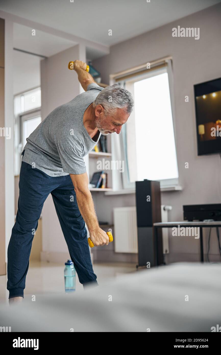 Energischer Mann im Alter, der zu Hause körperliche Übungen macht Stockfoto