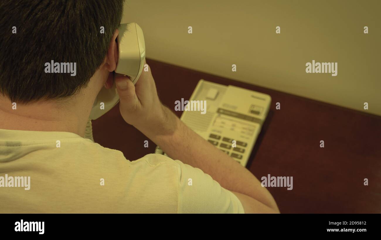 Ein Mann, der auf einem Festnetztelefon spricht Stockfoto